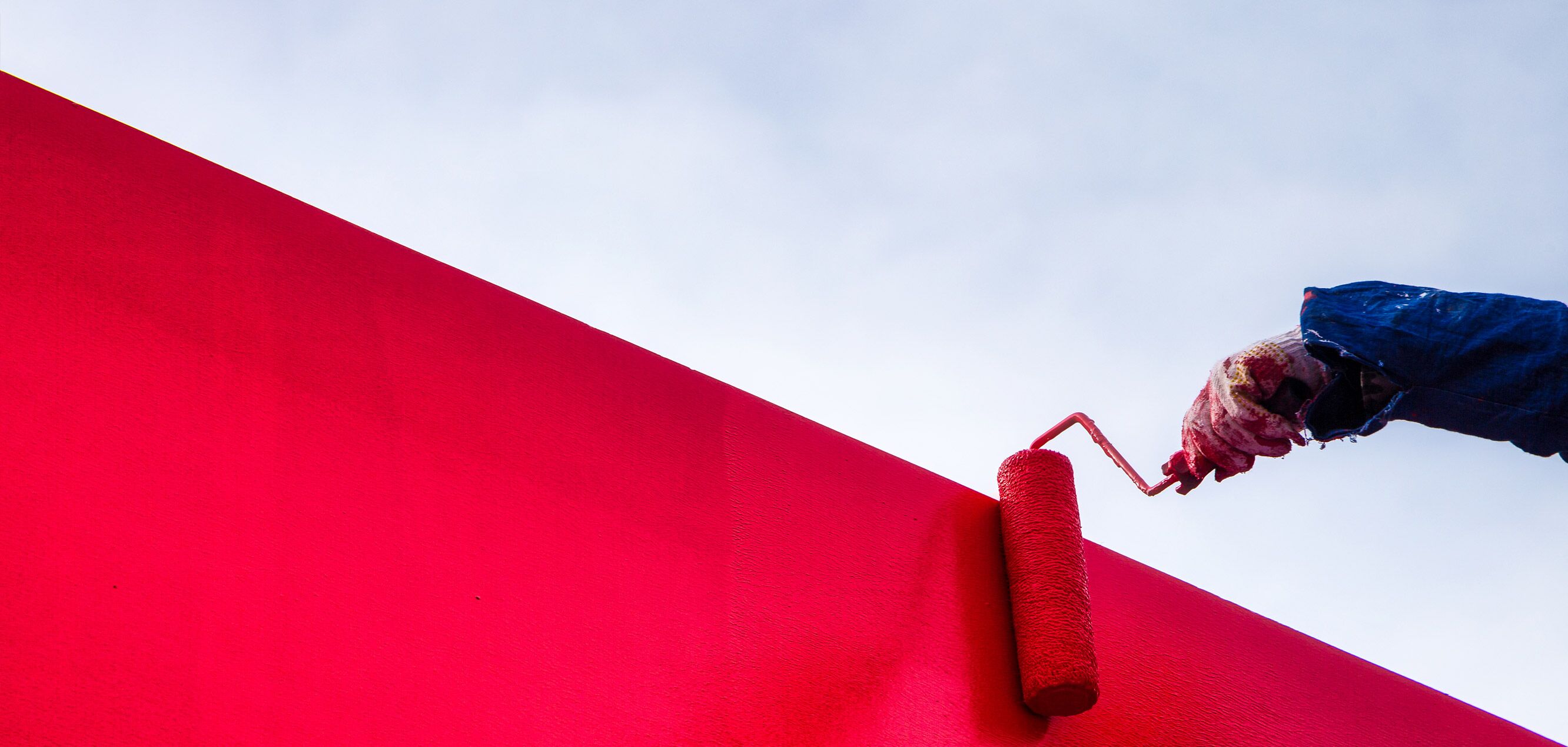 Malerarbeiten an einer roten Wand mit Farbroller